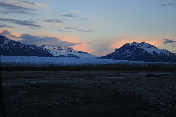 Snow-capped mountains and a glacier under a pastel sky at dusk