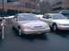 1997 Ford Crown Victoria - A tan 1997 Ford Crown Victoria is parked in a lot next to another sedan.