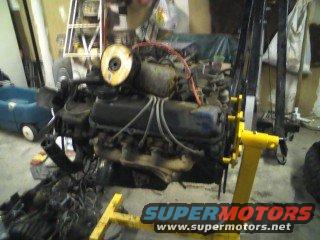 Engine on a yellow stand, with red wires and a yellow circular component. SuperMotors logo visible
