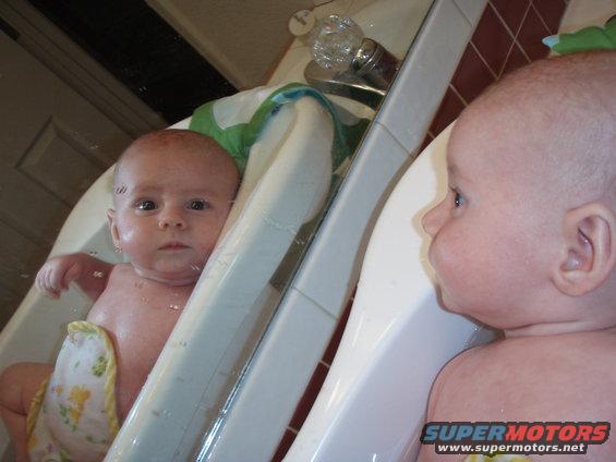 Baby in bathtub looking at reflection