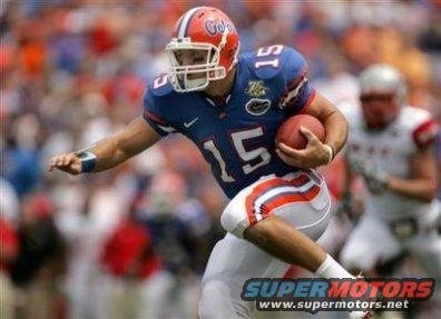 Football player in blue uniform with orange trim, number 15, running with a football