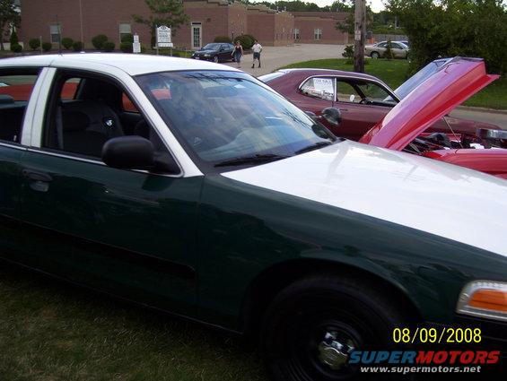 Green and white sedan parked next to a red muscle car with hood open. Date stamp reads 08/09/2008