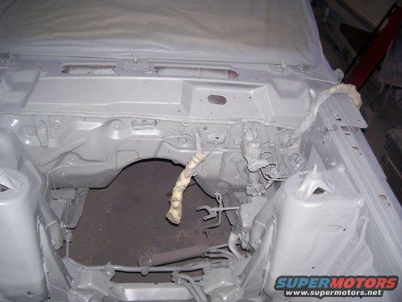 car's engine bay, covered in primer, undergoing restoration. Some wiring is visible