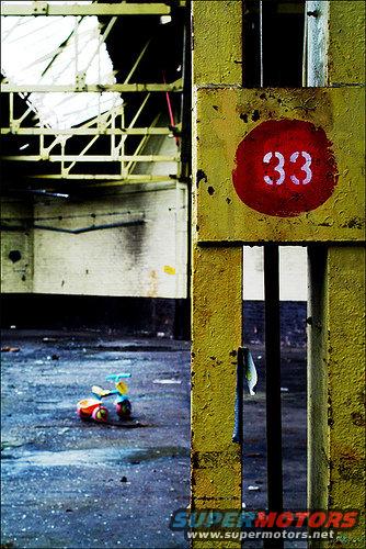 Abandoned industrial area with a yellow post marked '33' and a toy tricycle on the ground