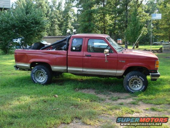 Red Ford Ranger pickup truck, extended cab, with off-road tires and roll bar. Two-tone paint with tan lower section