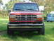 1984 Ford Bronco II - Front view of a red Ford SUV with a lifted suspension and off-road tires parked on grass.