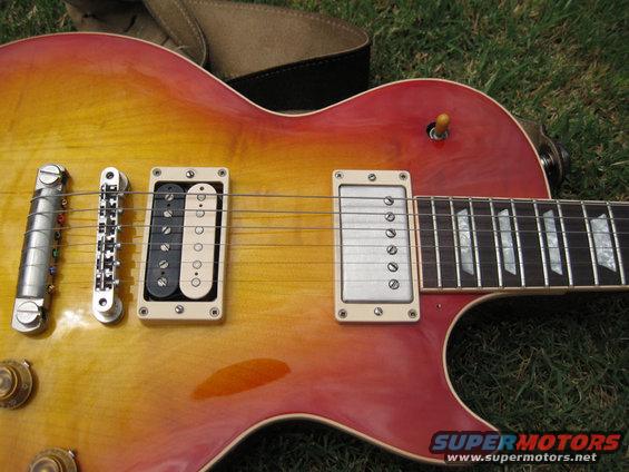 Close-up of a sunburst electric guitar body with two pickups and a strap