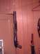 1991 Yugo Cabrio - A shotgun and a sword are displayed on a wood-paneled wall.