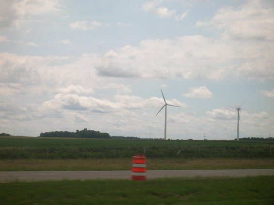 Wind turbines stand tall in a green field under a cloudy sky