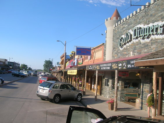 Street scene with shops and parked cars under a blue sky