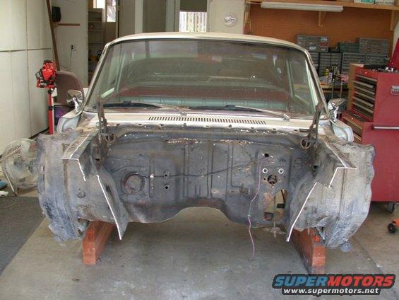 Car body with engine bay completely disassembled, supported by wooden blocks