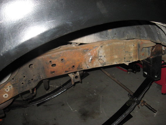 Rusted frame and leaf springs visible under a dark fender