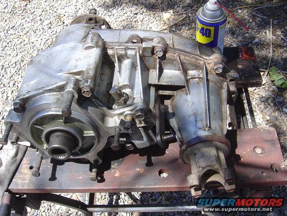 Aluminum transfer case with input and output shafts, sitting on a metal table. Can of WD-40 is nearby