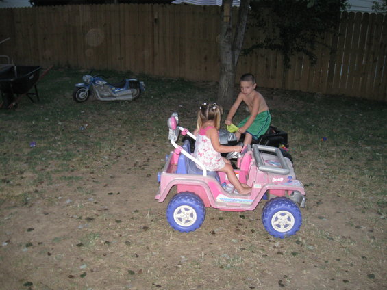 Pink toy Jeep with two children, blue toy motorcycle in background