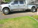 2008 Ford F-450 - A silver Ford F-450 pickup truck is parked on a driveway, equipped with a camper shell for extended travel.