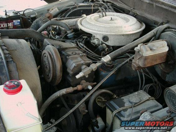 Engine bay of a 1979 Ford F-150, showing the V8 engine, air cleaner, AC compressor, and battery