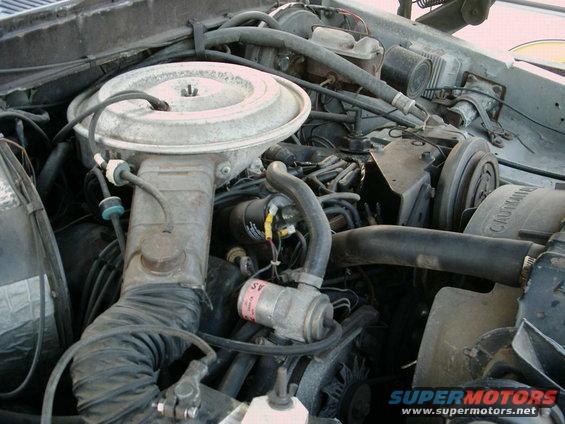 Engine bay with air cleaner, hoses, and engine components visible. Watermark reads SUPERMOTORS.NET