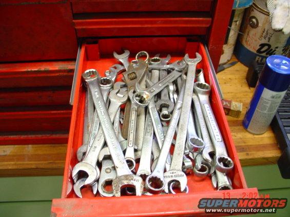 Drawer of wrenches in a red toolbox. Some text visible on tools and a spray can