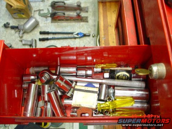 Red toolbox drawer filled with sockets, wrenches, screwdrivers, and a key in the lock