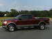 2005 Ford F-150 - Maroon 2005 Ford F-150 pickup truck parked on asphalt with trees and a house in the background.