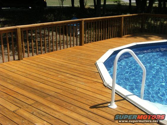 Wooden deck surrounding an above-ground pool with white ladder