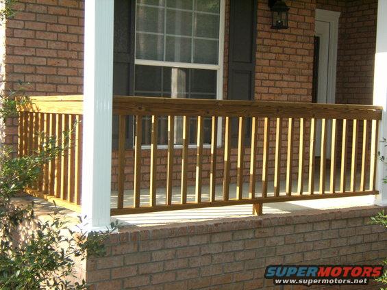 Wooden porch railing with brick foundation and white column