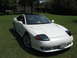 1992 Dodge Stealth - This Mitsubishi 3000GT features pop-up headlights and a black roof, parked on a grassy lawn.