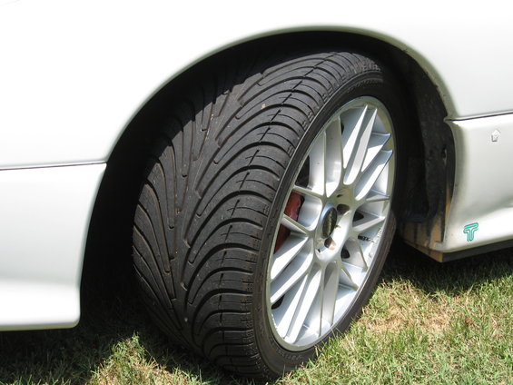 Close-up of a white car's front wheel and fender with a silver multi-spoke rim