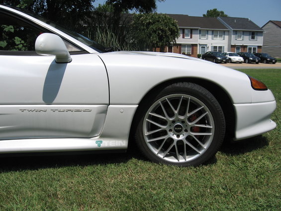 Side view of a white sports car with 'TWIN TURBO' badging and aftermarket wheels