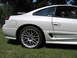 1992 Dodge Stealth - Side view of a white sports car with aftermarket wheels parked on grass.