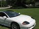 1992 Dodge Stealth - White 1992 Dodge Stealth with a black roof and distinctive pop-up headlights, seen from a 3/4 front angle.