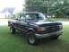 1989 Ford Bronco - This dark blue Ford F-150 pickup truck is shown from the front 3/4 angle.