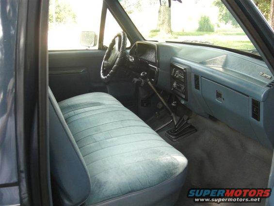 Interior shot of a truck's bench seat, dashboard, and steering wheel