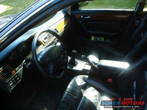 Interior shot of a car, showing the steering wheel, dashboard, gear shift, and leather seats