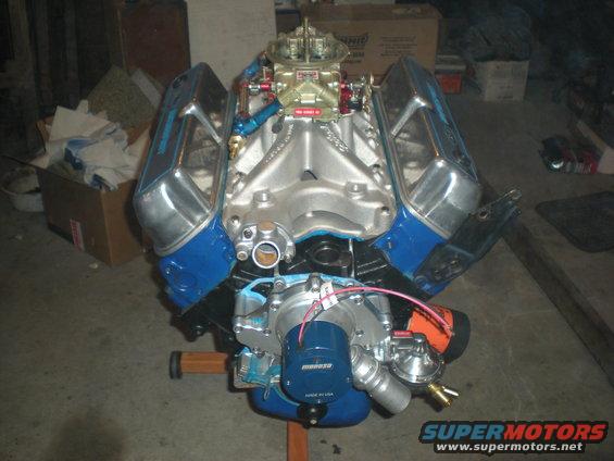 V8 engine with chrome valve covers and blue accents, mounted on an engine stand