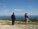 2008 Honda RANCHER - Two individuals survey a vast, hazy landscape from a rocky vantage point under a clear blue sky.