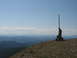 2008 Honda RANCHER - A person stands on a mountain summit next to a marker pole, overlooking a vast landscape of rolling blue mountains.