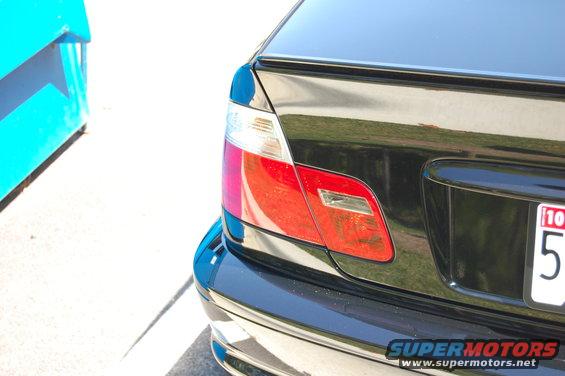 Black car's rear tail light assembly with red and clear sections, license plate visible
