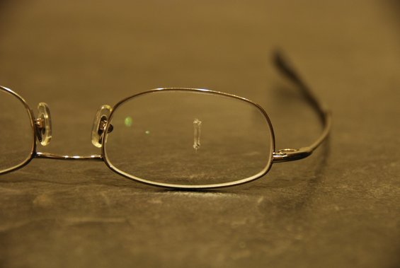 Close-up of eyeglasses with a small object stuck to the lens
