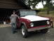 1968 Ford Bronco - A red 1968 Ford Bronco is parked outside a garage with a person standing beside it.