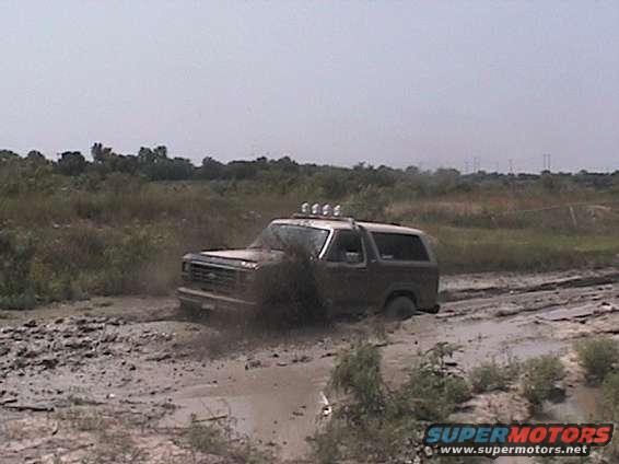Ford Bronco stuck in mud, front right wheel deep in mire. Light bar on roof