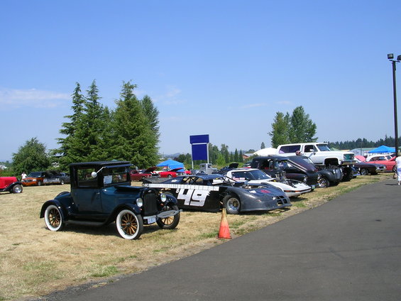 Several cars and trucks parked on a grassy field under a clear blue sky
