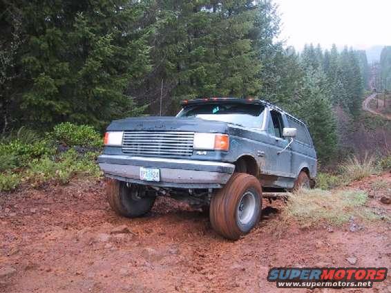 Dark blue SUV with large tires on a muddy trail. License plate reads IPX1824