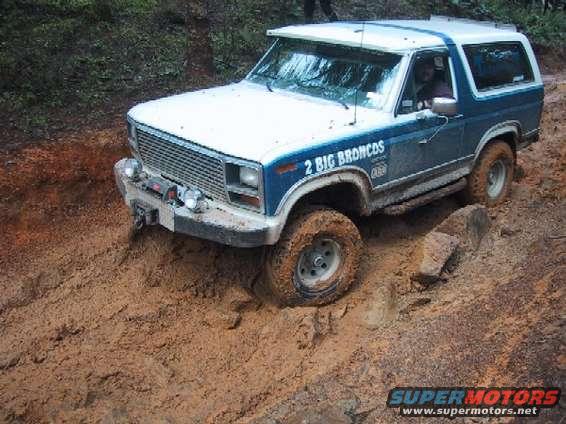 1980 Ford Bronco driving through thick mud, text on door reads '2 BIG BRONCOS'