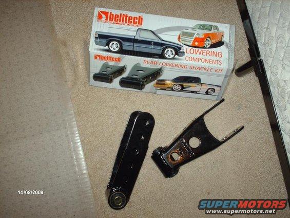 Belitech lowering components box with diagrams of trucks and two black metal lowering shackle parts on carpet