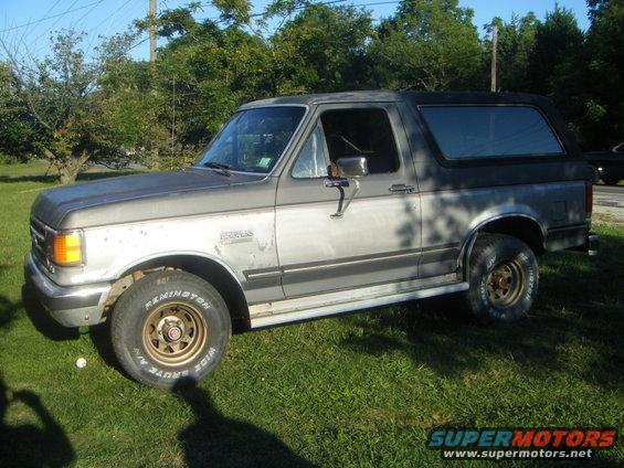 Gray Ford Bronco parked on grass. It has a two-tone paint job and aftermarket wheels
