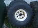 1979 Ford F-250 - A close-up of a large off-road tire mounted on a white wheel, showing its tread pattern.