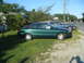 1979 Ford F-250 - A green coupe sits on a grassy lot next to a blue sedan, with a "For Sale" sign visible in the coupe's window.