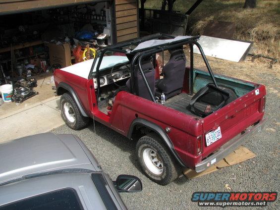 Red 1968 Ford Bronco with white top, roll cage, and aftermarket wheels