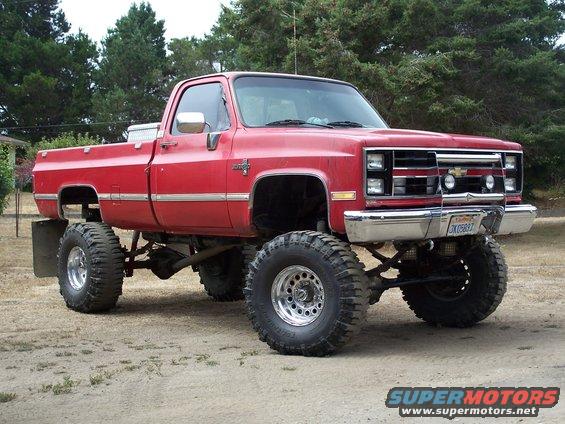 Red lifted pickup truck with chrome grille and large off-road tires